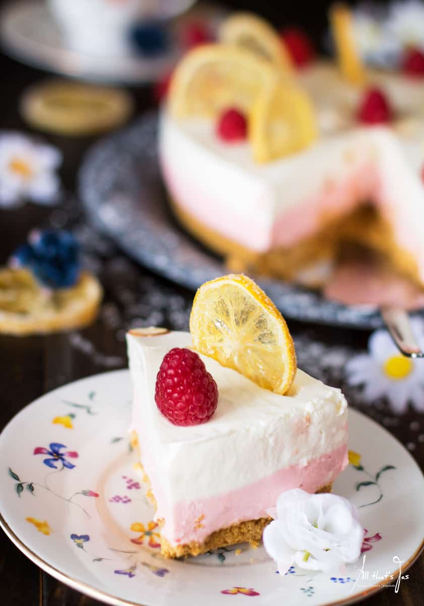 Slice of lemon and raspberry no bake cheesecake (one white layer on top followed by a pink layer nearest to the graham cracker crust)