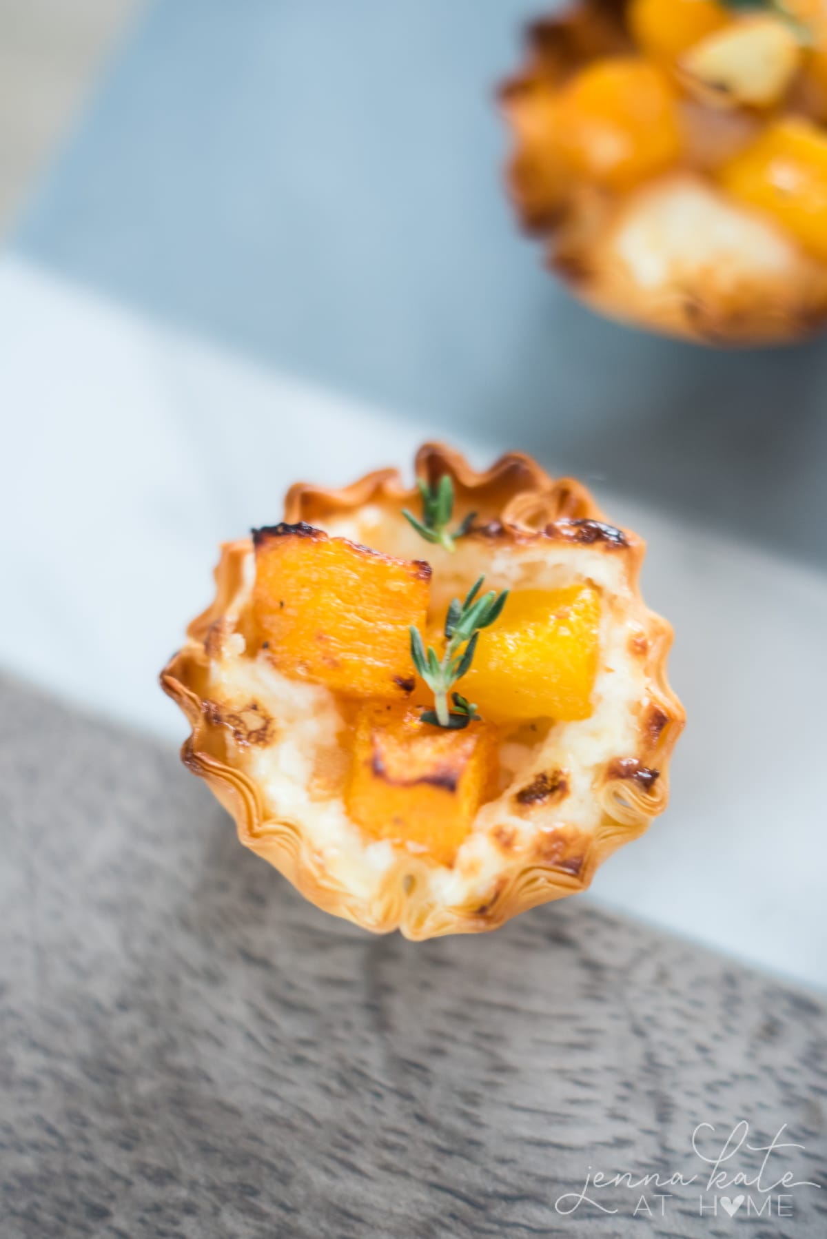 Close up of the baked butternut squash bite with a sprig of rosemary on top