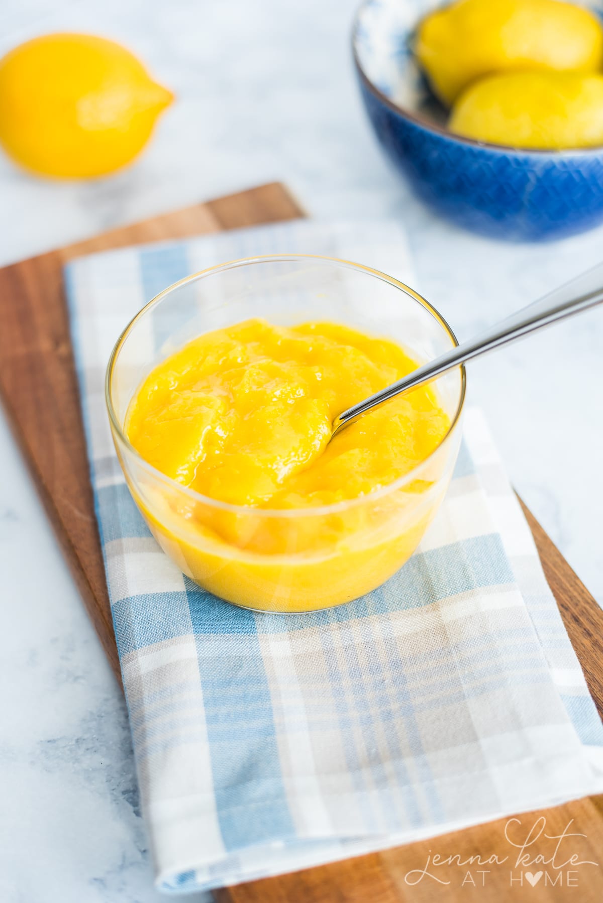 A bowl of lemon curd sitting on a table with a spoon in it