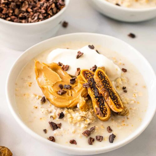 bowl of overnight oats topped with cacoa nibs, yogurt, and peanut butter