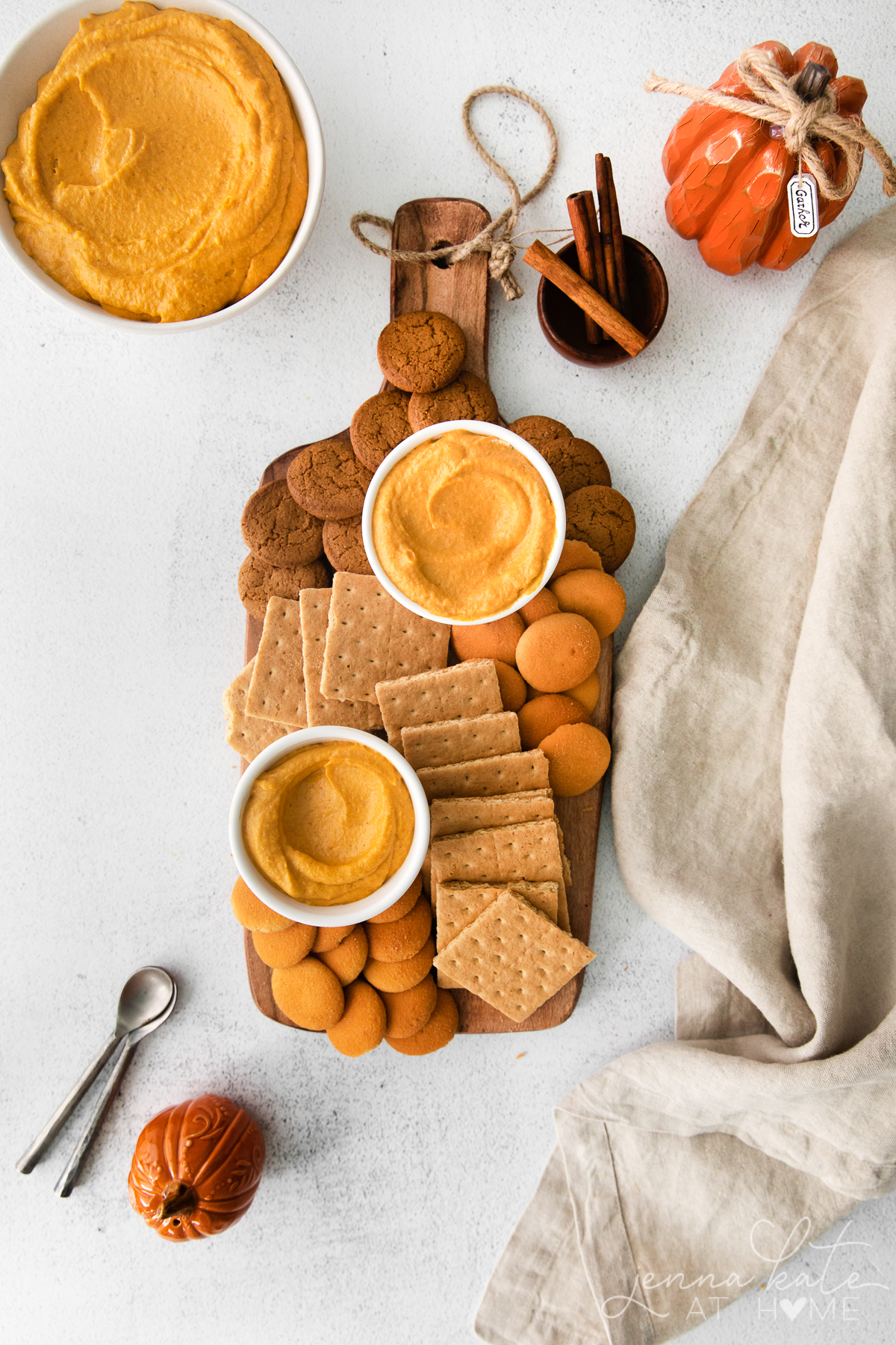pumpkin pie cheesecake dip on a bread board with graham crackers, nilla wafers and gingersnap cookies
