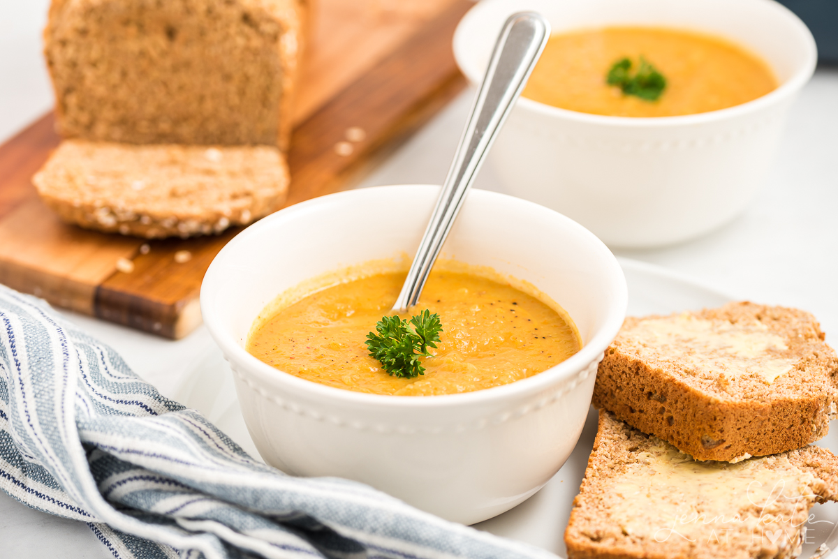 bowl of simple and classic vegetable soup with bread and more soup in the background