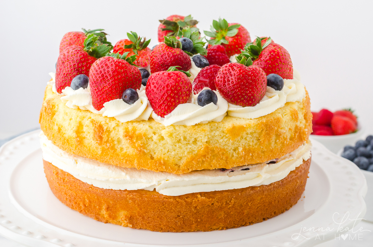 sponge cake filled with cream and topped with fresh fruits like strawberries, raspberries and blueberries