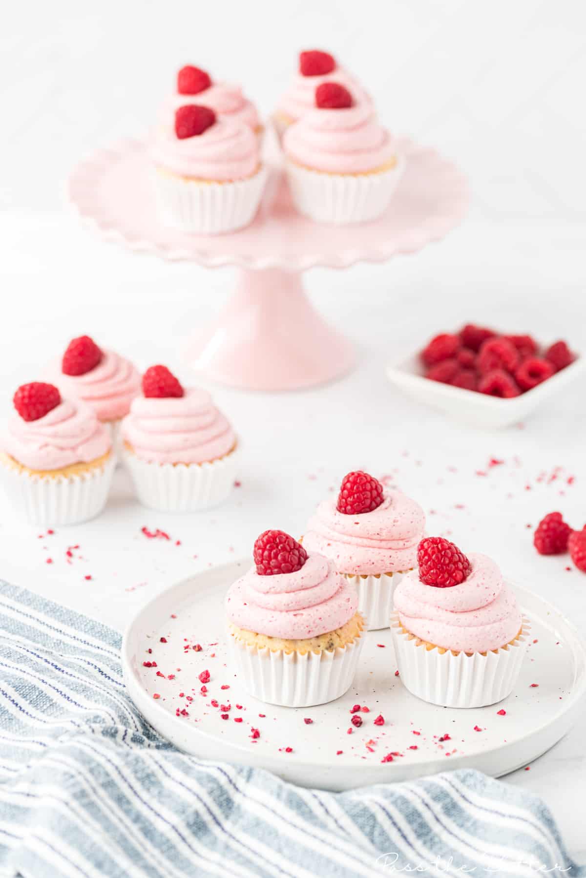 plate of raspberry cupcakes topped with frosting and a real raspberry
