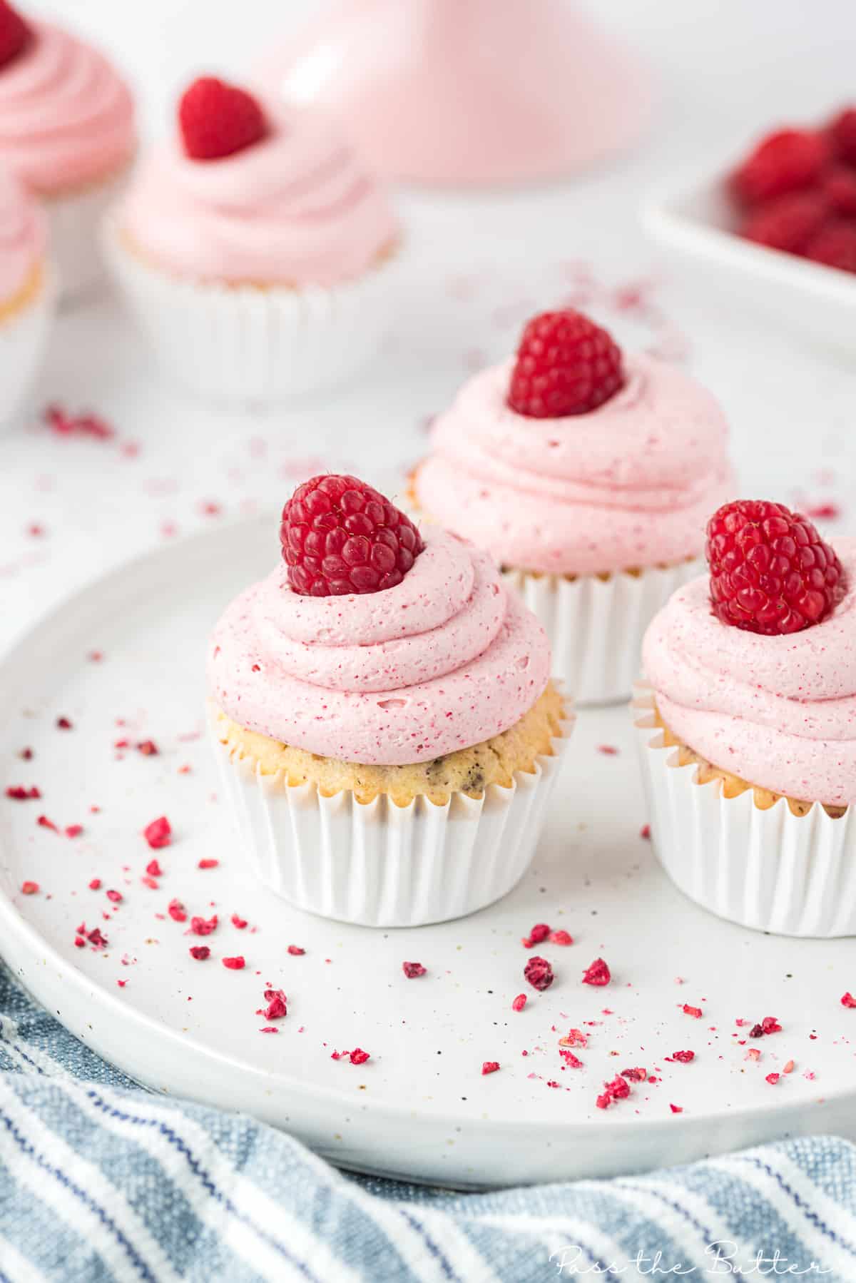 raspberry cupcakes with raspberry buttercream frosting sitting on a plate