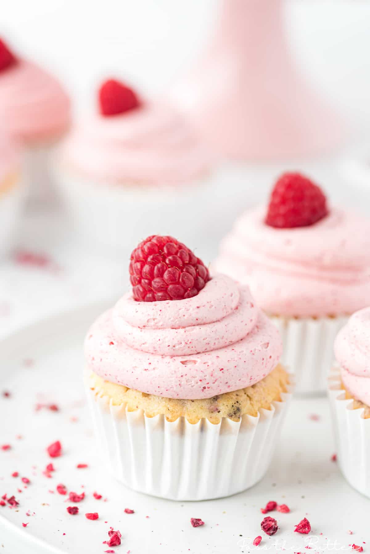 close up of the raspberry cupcake with raspberry frosting and a fresh raspberry on top