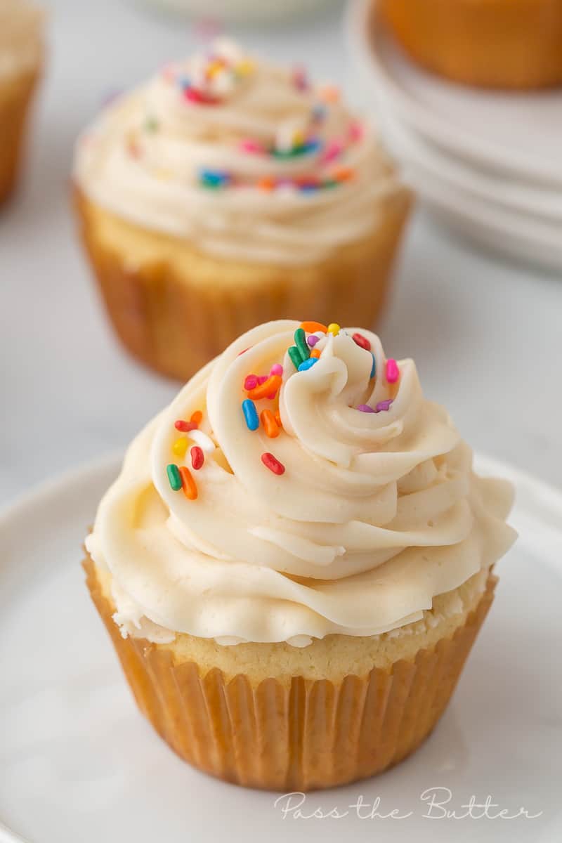 vanilla cupcake with vanilla frosting and colored sprinkles on a plate