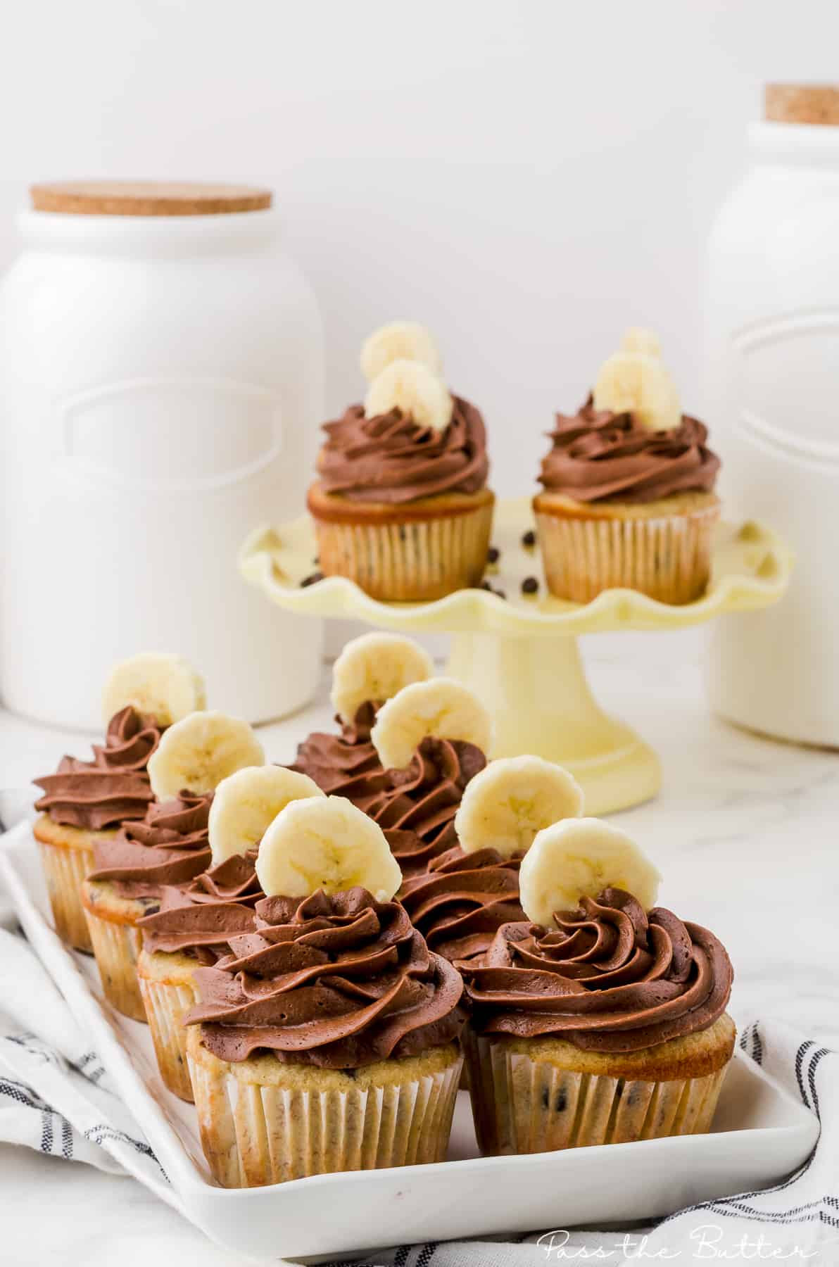 chocolate banana cupcakes on a plate with more on a stand behind