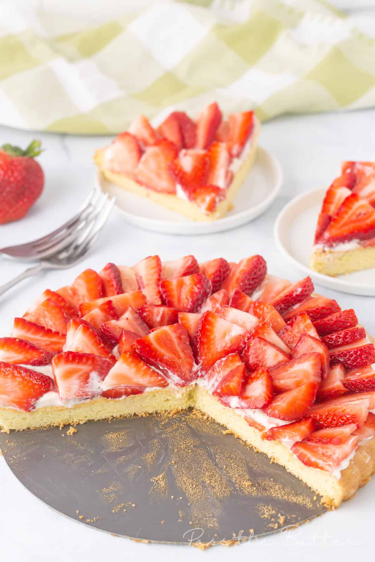 View of strawberry flan with two pieces cut out and showcasing the layers of strawberries.