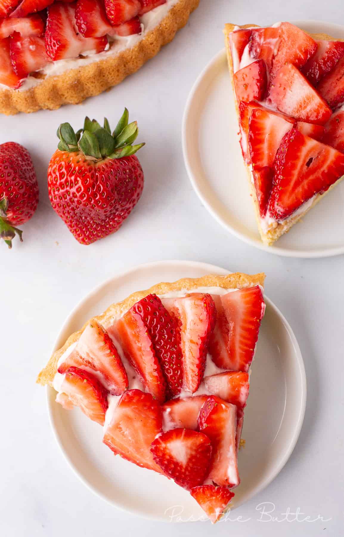 A slice of strawberry flan on a plate with fresh strawberries.