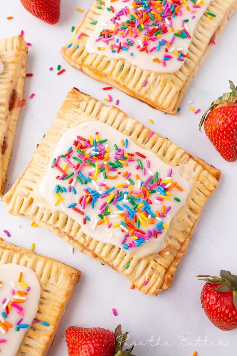 Strawberry pop tarts on a marble countertop.  Topped with glaze and sprinkles.