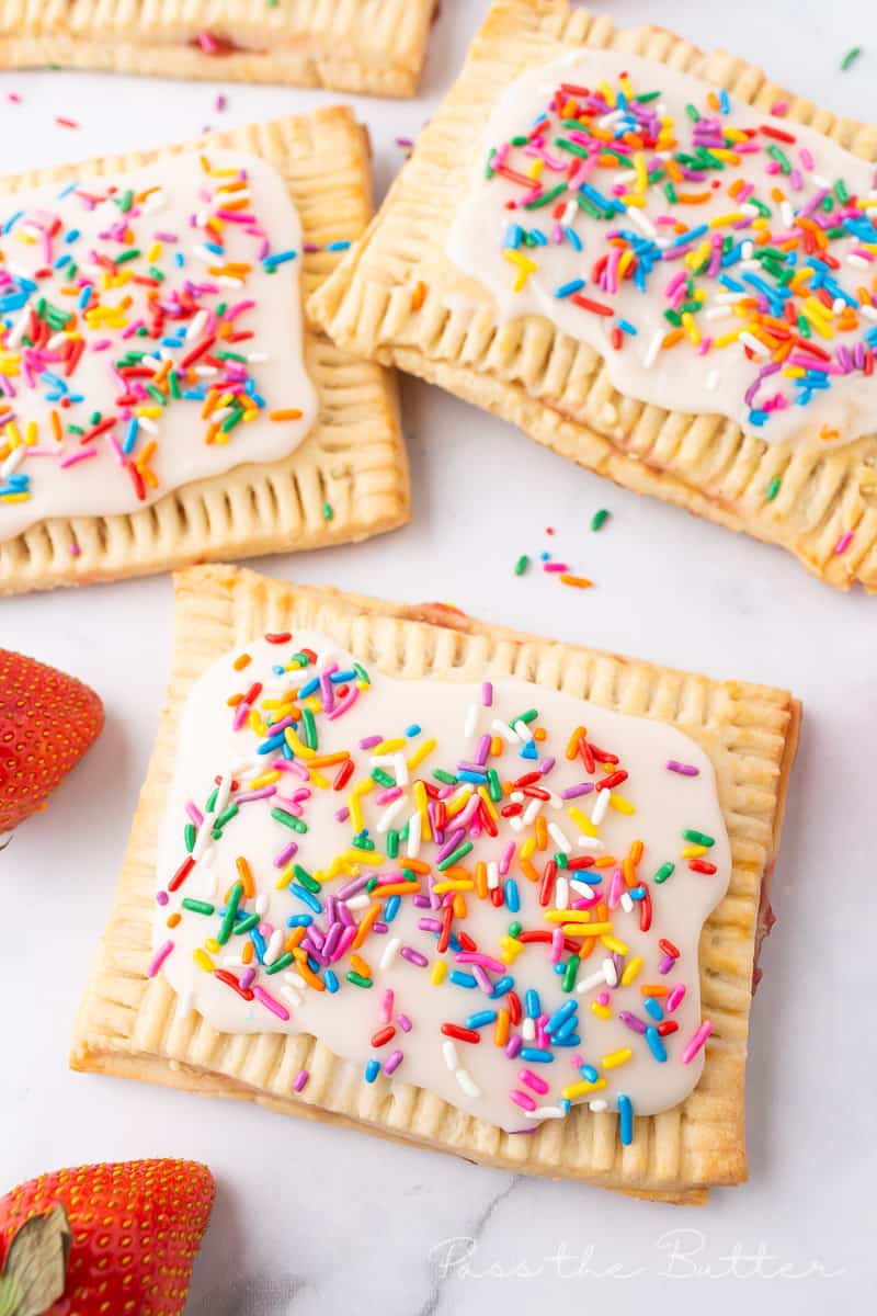 strawberry pop tarts with glaze and sprinkles on a marble countertop.