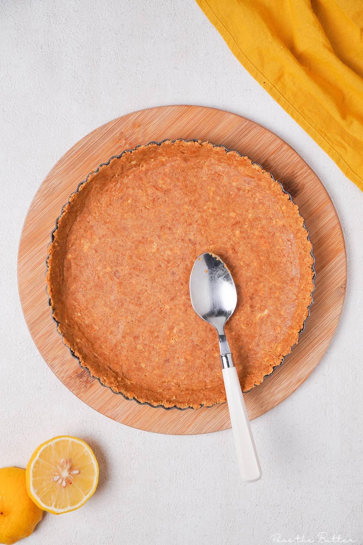 Graham cracker crust in pie plate with spoon.
