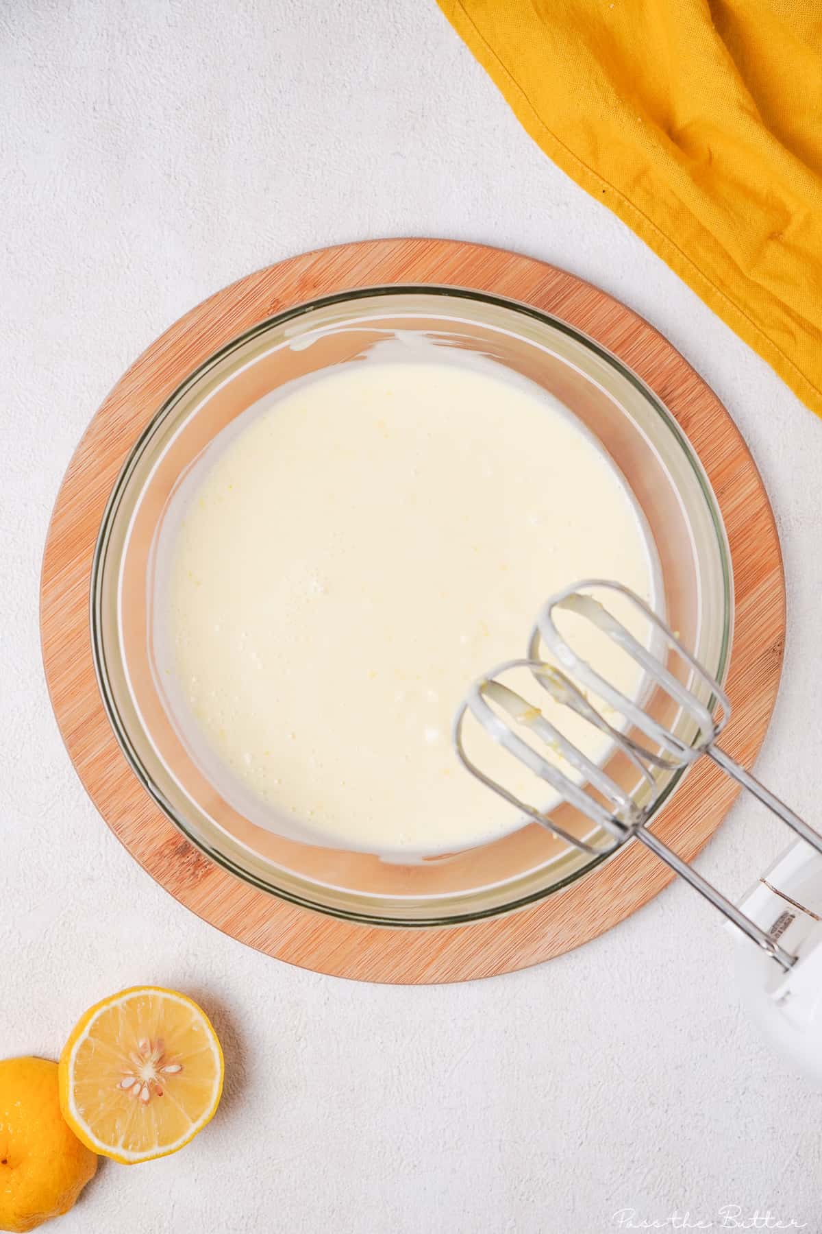 Ingredients for no bake lemon tart in bowl with hand mixer.